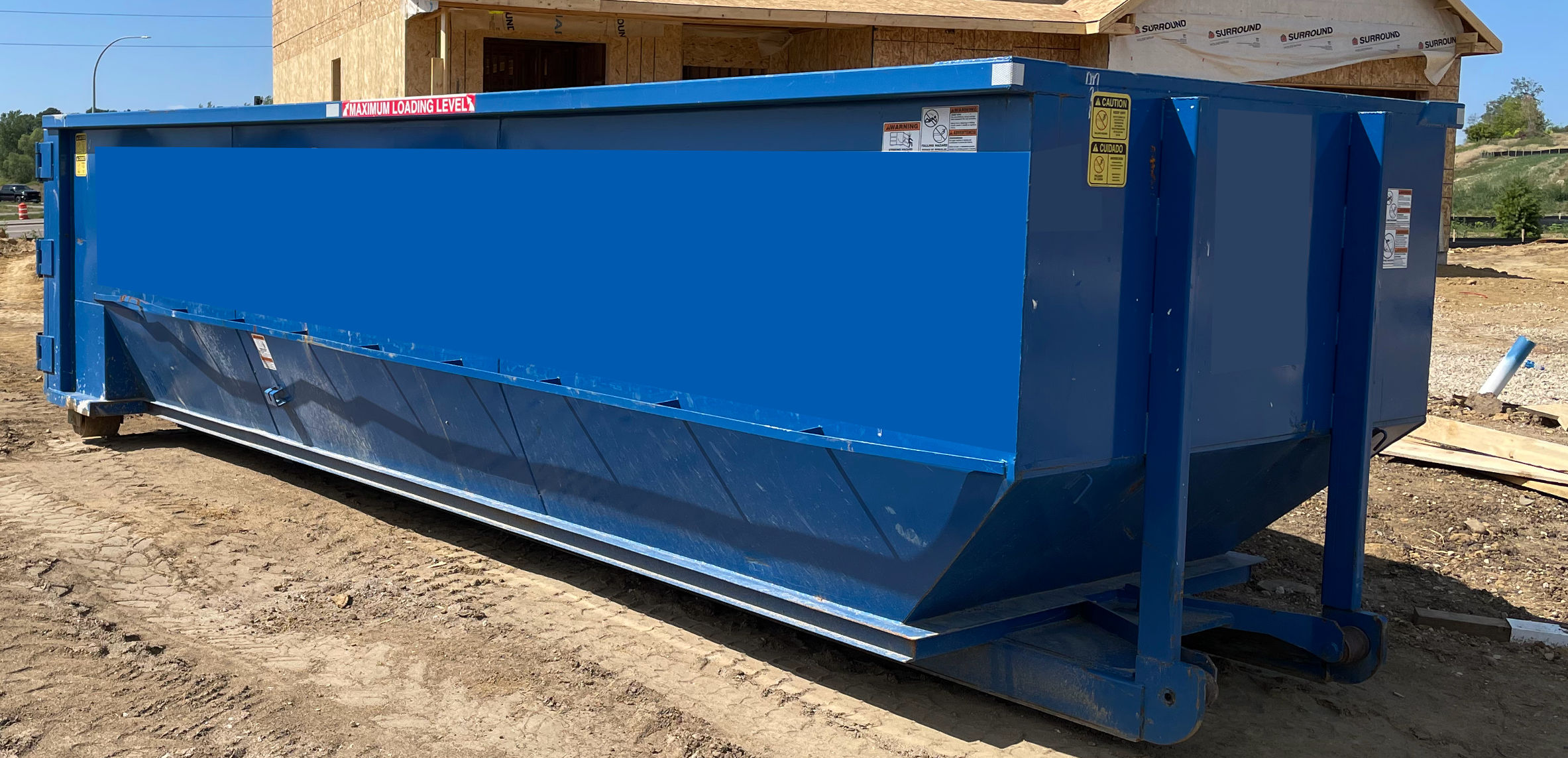 Blue dumpster being placed on the driveway of residential area