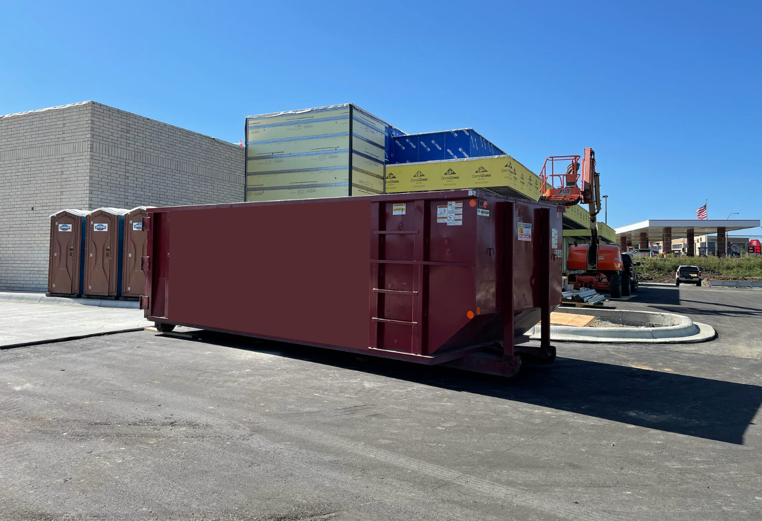 Maroon dumpster being placed on the street of commercial project